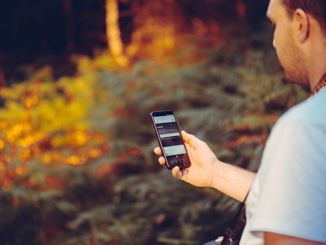 Hombre sosteniendo la app de flivo para pagar desde cualquier lugar